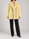 butter-yellow mid-hip plush faux-fur coat with broad notched collar and straight sleeves, front view on a model