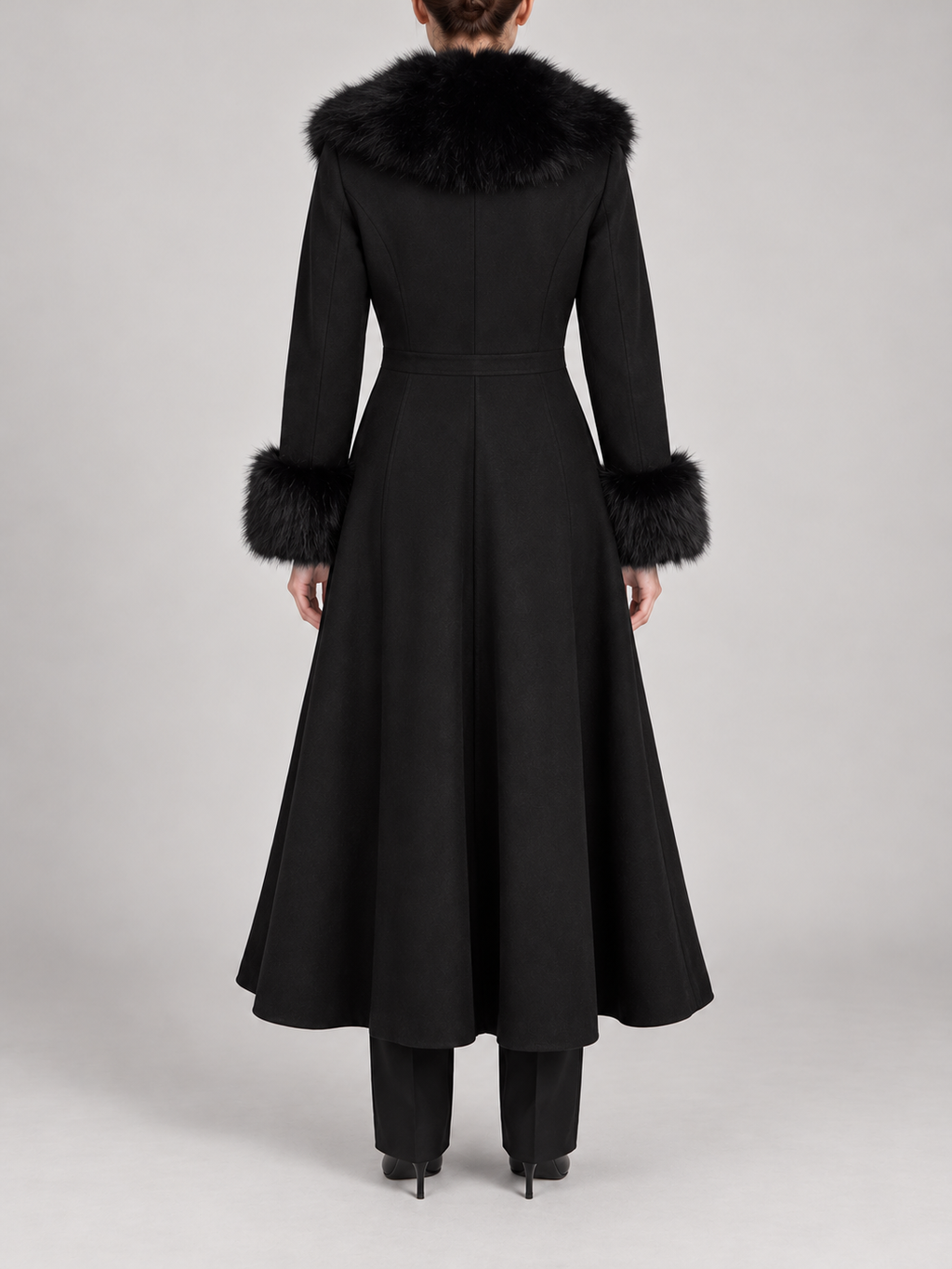 black calf-length flared coat with fitted waist, voluminous faux-fur shawl collar and furry cuffs, back view on a model
