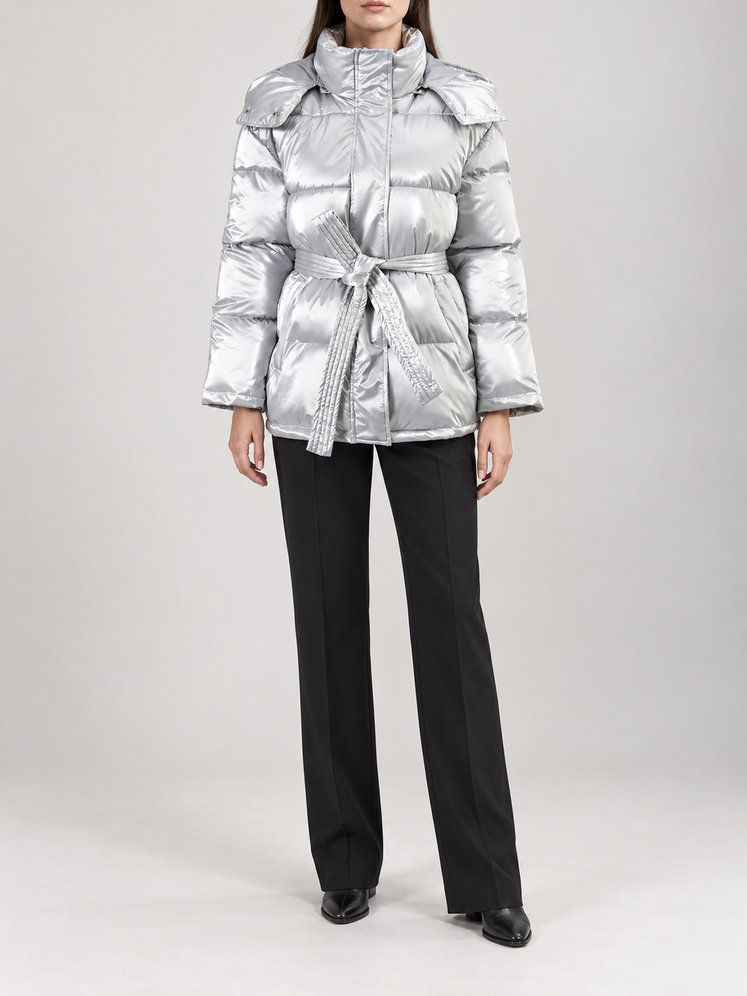 silver glossy quilted hooded puffer jacket with self-tie waist belt and horizontal panels, front view on a model