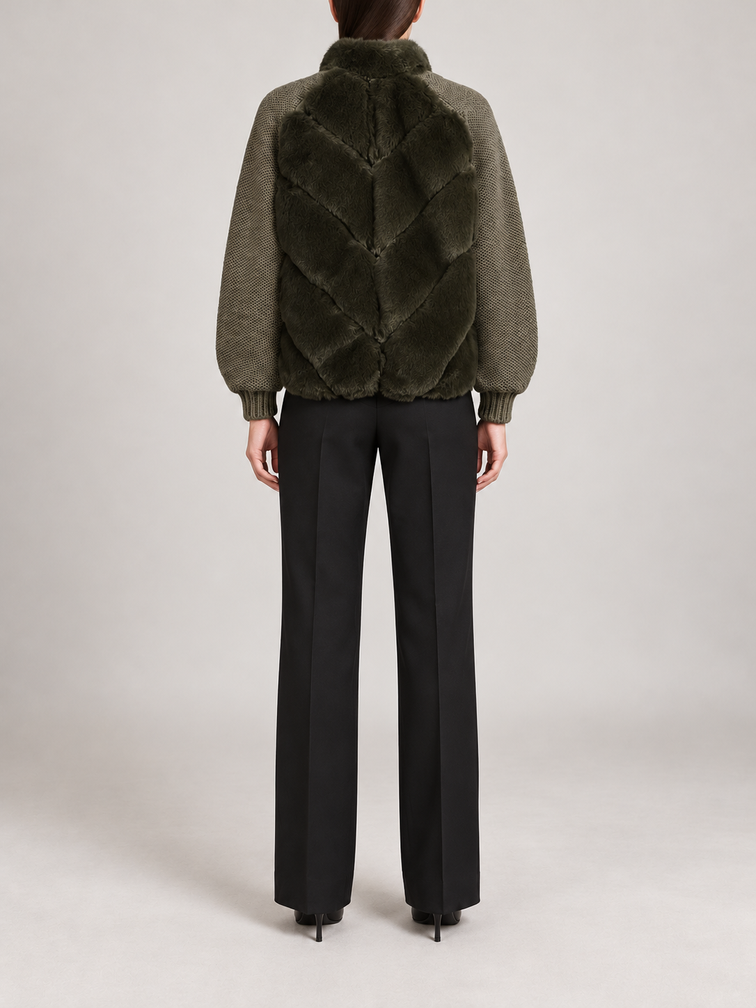 dark olive short jacket with chevron faux-fur body panels, olive knitted sleeves and ribbed cuffs, back view on a model