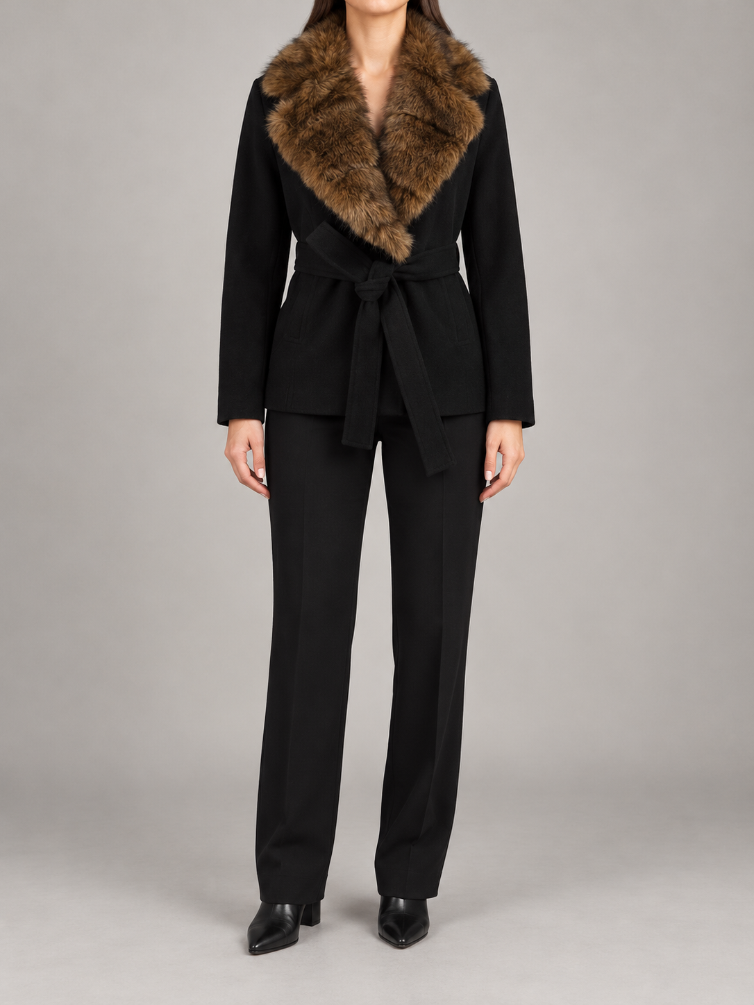 black hip-length wrap coat with brown faux-fur shawl collar and fabric waist tie, front view on a model