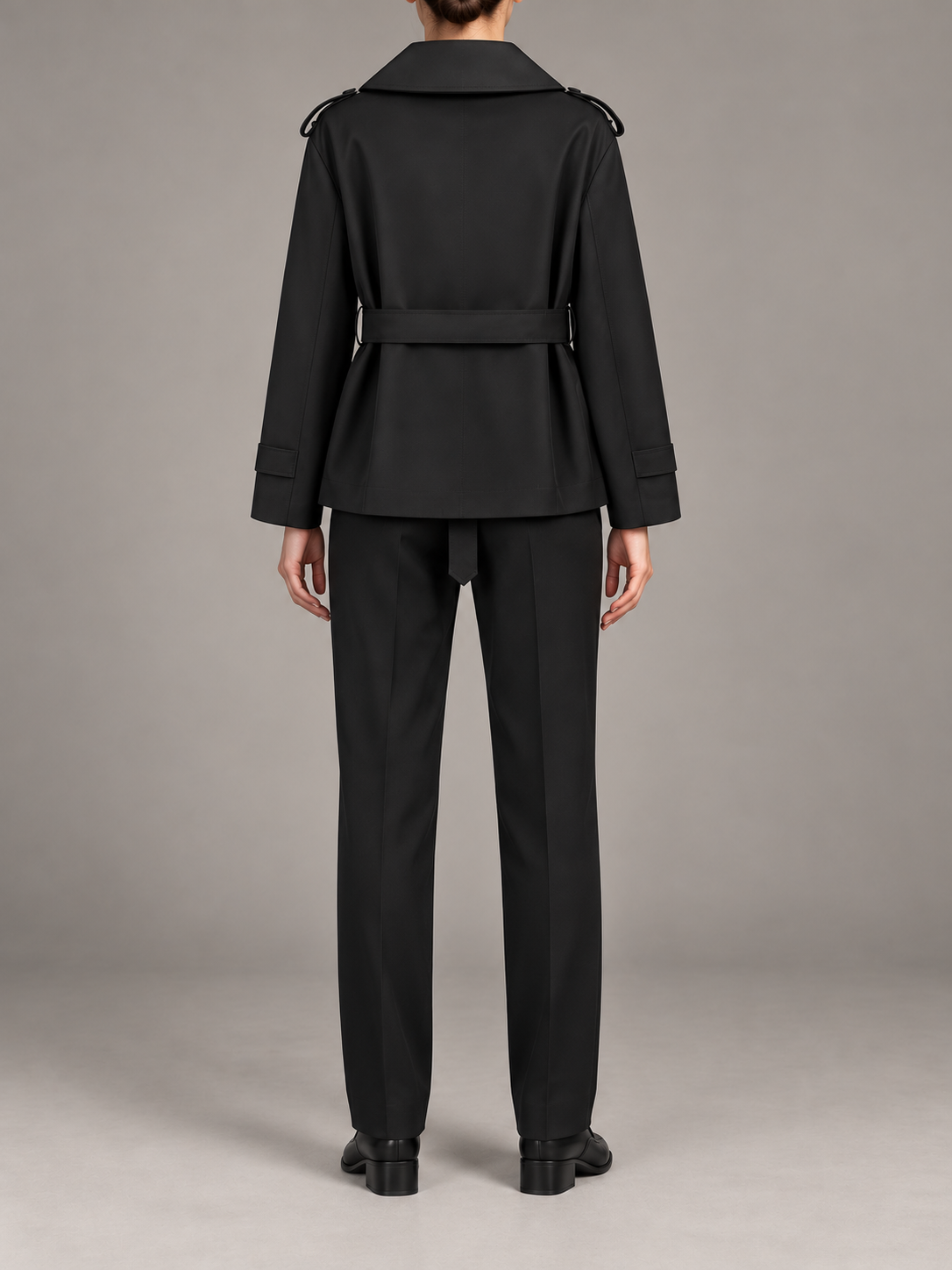 black double-breasted short trench with wide V-neck lapels, waist tie and buttoned cuff tabs, back view on a model